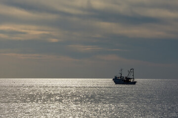 fishing trawler on silvery shimmering sea with space for text