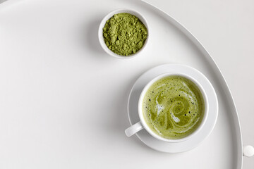 Green matcha tea with milk in cup on white table and white backgriund