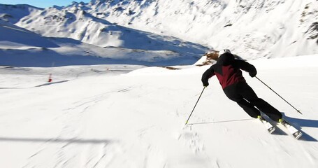 Cinematic downhill skiing in beautiful alpine mountain landscape. Slow motion ski turns of a young male ski athlete in the Tyrolean mountains i beautiful sun light and fresh snow. Skiresort Ischgl