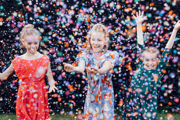 Young girls having fun celebrating under a confetti shower at party outdoor