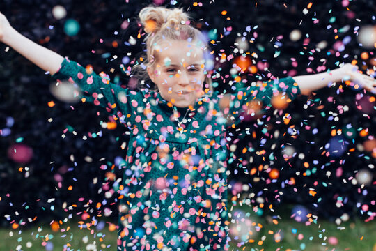 beautiful smiling little girl under a shower of confetti - birthday party carefree celebration concept
