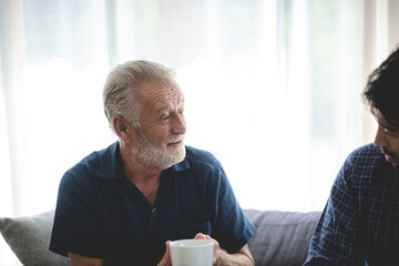 Adult hipster son and old senior father stay for work at home, two generations have a beard talking...