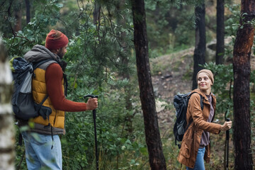 pleased couple looking at each other trekking with hiking sticks in forest