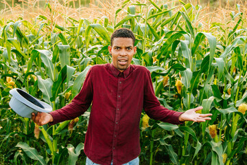 African American farmer looks at camera confused and puzzled. African farmer man in red shirt and...