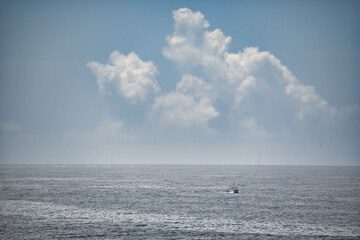 Barco solitaria en el océano Atlántico y nubes tormentosas de fondo, A Coruña, Galicia, Costa de la muerte, España.