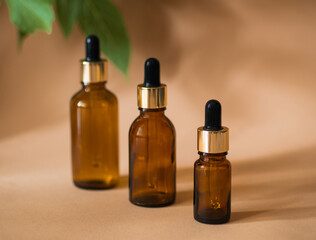 Three cosmetic bottles with a pipette  on a beige background