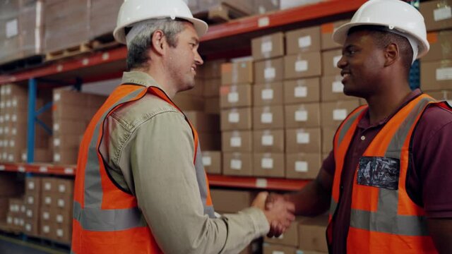 Colleagues making looking at digital tablet business deal handshaking in factory warehouse 