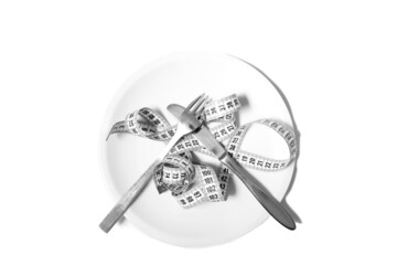 Measuring tape on a white dinner plate with a knife and fork on it. Illustrating healthy eating and dieting. Isolated on white background.