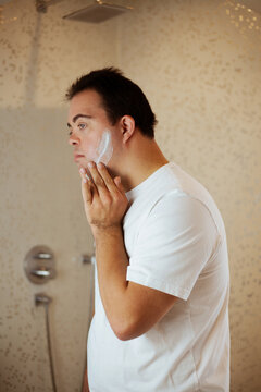 Young Man With Down Syndrome Applying Shaving Cream In The Bathroom