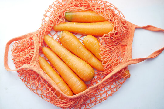 fresh carrots in shopping bag on white 