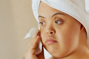 Young biracial woman with Down Syndrome removing make-up with wipe in the bathroom