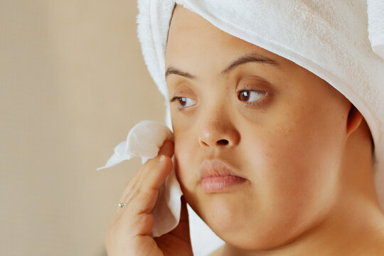 Young biracial woman with Down Syndrome removing make-up with wipe in the bathroom