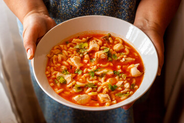 Fish soup with pasta in the hands of the cook.