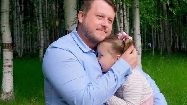 Portrait of a couple hugging happy father and daughter 3-4 years old while walking in the park