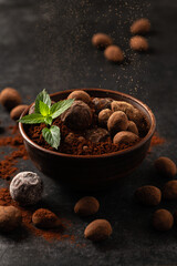natural chocolate truffles with mint in decorative dishes, dark background, dark mood
