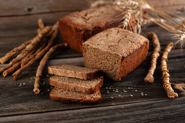 Rye homemade bread with bread sticks on a wooden old table