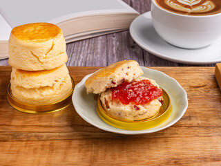Scones traditional English delicious freshly baked homemade with strawberry jam and served on a wooden tray with a coffee cup. Top view. Dessert, beverage, and relaxation concept