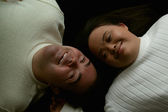Portrait of young biracial couple with Down Syndrome next to each other and laughing