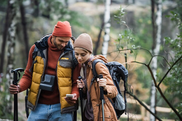 Fototapeta premium couple looking at smartphone while trekking in woods