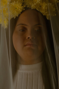 Portrait of young biracial woman with Down Syndrome  with flowers underneath veil