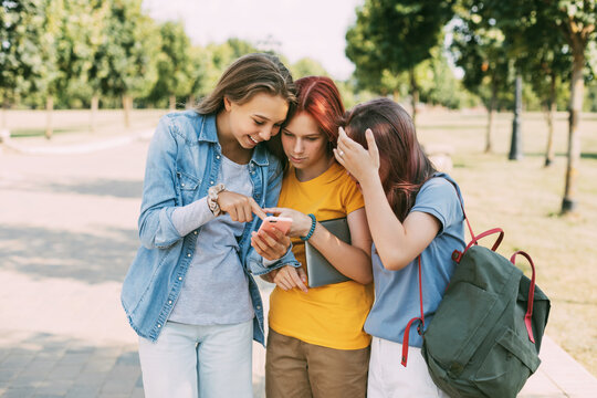 Three charming friends take selfies with their phone on the way to school. The concept of friendship. Education, training, back to school