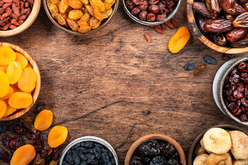 Natural Dried fruits in bowls. Healthy food snack: sun dried organic mix of apricots, figs, raisins, dates and other on wooden table, top view
