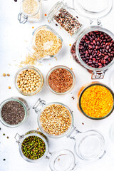 Grocery, home stocks in plastic free storage and jars. Various beans, grains, cereals, legumes, seeds in reusable cans. White table. Zero waste and sustainable lifestyle