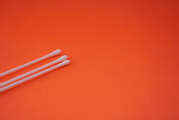 Stock photo of a pile of white cotton buds that are lined up and neatly arranged so that it looks aesthetic. Isolated on an orange background. Medical equipment Industry,design,website photo,Pattern