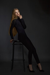 Fototapeta na wymiar beautiful girl blonde teenager in black clothes posing in the studio on a dark background