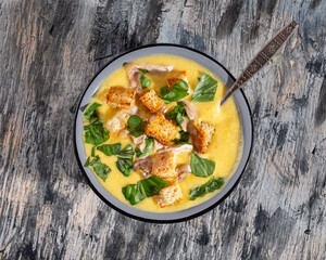 Puree soup with chicken meat and toasted croutons in a deep blue plate