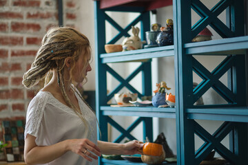 hostess of the ceramic workshop lays out her ceramic dishes on the shelves. feng shui concept....