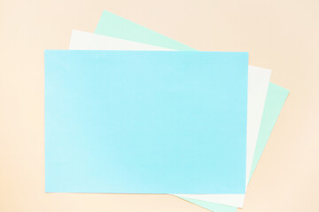 Blank sheets of blue colored paper on a beige background. Layout, copy space.