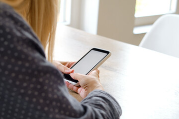 A girl is holding a modern smartphone, sending a text message or using an application on her mobile phone. Gadget addiction. Smartphone close-up. Focus on the phone screen