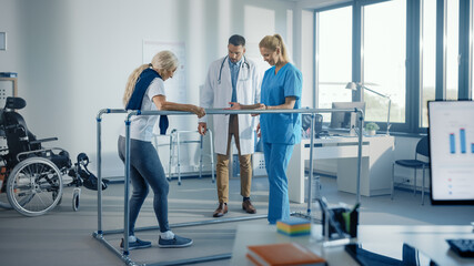 Hospital Physical Therapy: Strong Senior Female Disabled Patient with Injury Making First Steps, Walks Holding for Parallel Bars. Physiotherapist, Rehabilitation Doctor Applaud, Encourage Old Woman