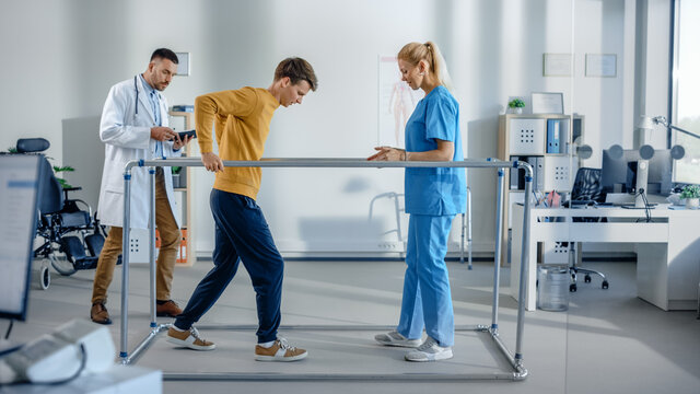 Hospital Physical Therapy: Strong Patient with Back Injury Making First Slow Steps, Walks Holding for Parallel Bars. Physiotherapist, Rehabilitation Doctor Assist, Help, Encourage Disabled Person
