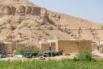 scenery of rocky mountain, traditional stone  houses of shibam hadramaout, and piled up tires in...