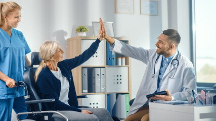 Hospital Physical Therapy: Strong Senior Female in Wheelchair, Talks to a Friendly Rehabilitation Physiotherapist Doctors Gives High Five. Successful Rehabilitation of Disabled Patient