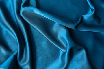 Blue silk drapery and upholstery fabric from the courtyard. Blue satin, silky fabric, wave, draperies. Beautiful textile backdrop. Close-up. Top view