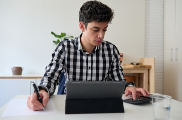 Young freelancer doing income tax return on laptop with calculator