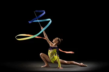 Fototapete One sportive emotional girl, rhythmic gymnastics artist isolated on dark background in ray of light. Concept of sport, action, aspiration, beauty, active lifestyle © master1305