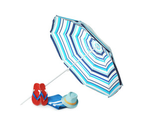 Open striped beach umbrella, towel, flip flops and hat on white background