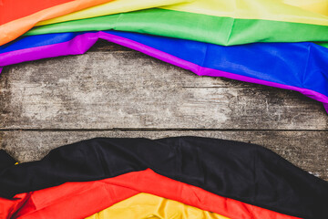 two flags on a wooden table, one flag is germany the second ist the rainbow flag