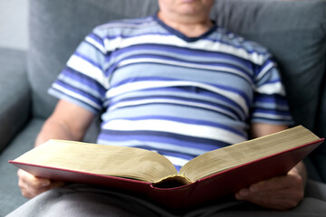 close-up of thick book in dark red cover, family bible, old man, senior reads, concept eternal values, education, fiction, meet old age with dignity, studying sacred Christian texts