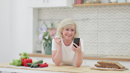 Old Woman doing Video Call on Smartphone in Kitchen