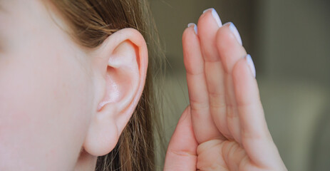 the girl put her hand to her ear. the girl is listening. the girl's ear hurts. the girl has an ear...