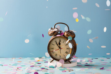 Close up of  vintage alarm clock and paper colored confetti. Holiday concept