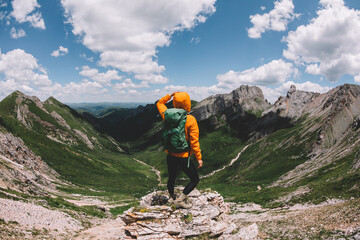 Successful woman backpacker hiking on sunset alpine mountain peak