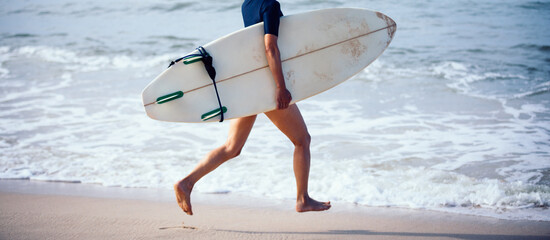 Surfer woman running with surfboard on the beach