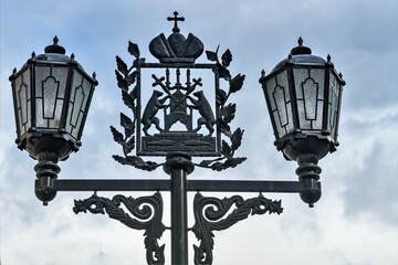 Fototapeta na wymiar Russia, Veliky Novgorod, August 2021. Coat of arms of the city on vintage lanterns against the sky.