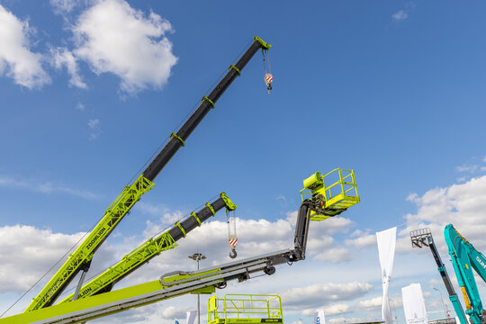 New Zoomlion construction equipment at the Bauma CTT Russia 2021 construction industry fair. Cranes booms and telescopic cradle against a blue cloudy sky background. Moscow, Russia - May 25-28, 2021